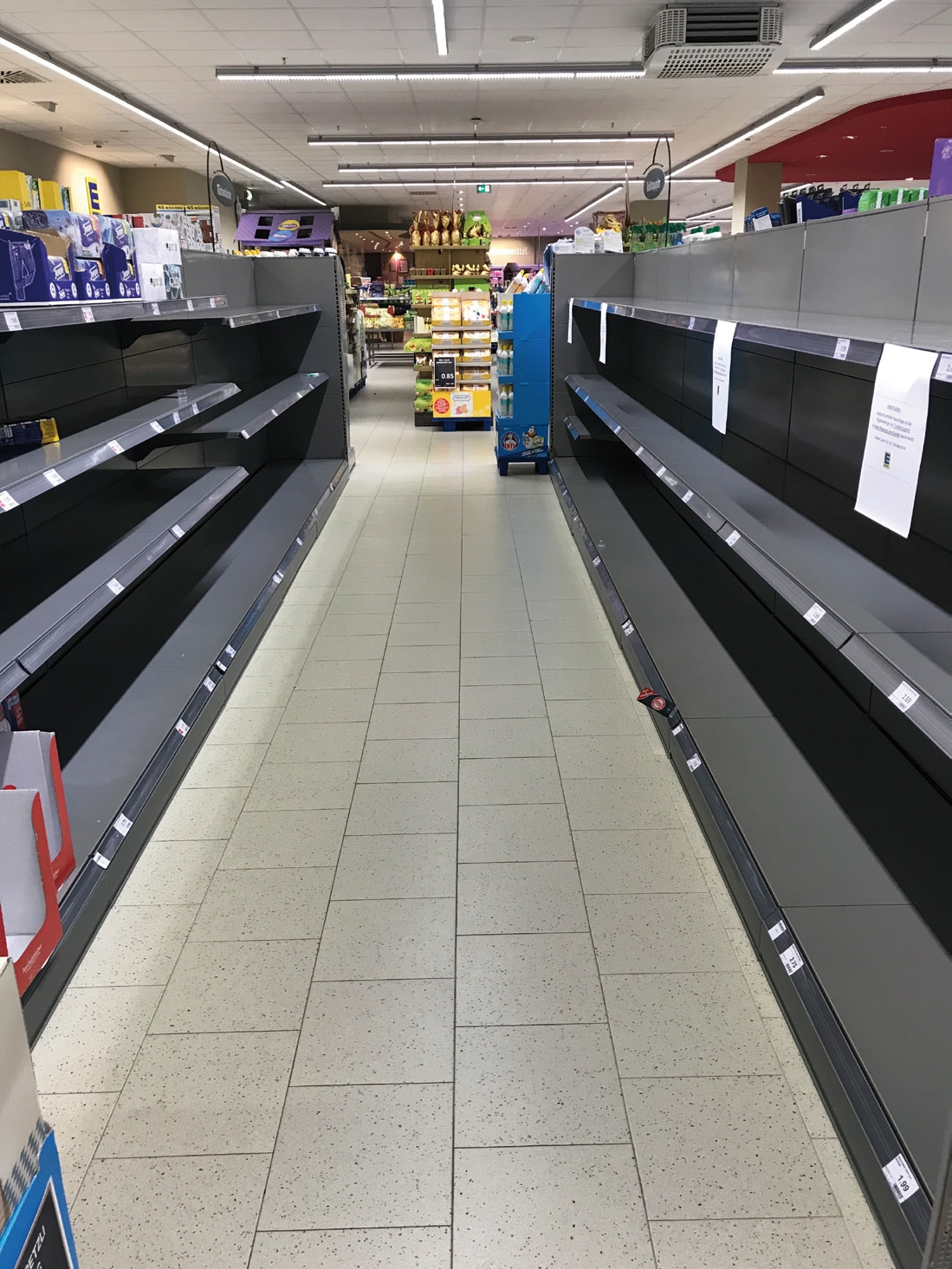 Leere Regale im Supermarkt zeugen von Hamsterkäufen. Hier sollten Toilettenpapier und Küchenrollen liegen.